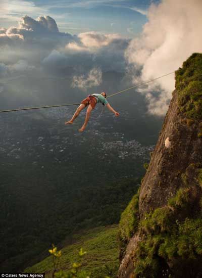 بالصور..متهور يأخذ قسطًا من الراحة مستلقيًا على سلك بارتفاع 3.000 قدم فوق أفق ريو دي جانيرو